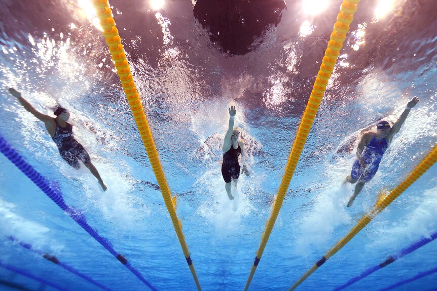 Three female swimmers during a race photographed from underwater