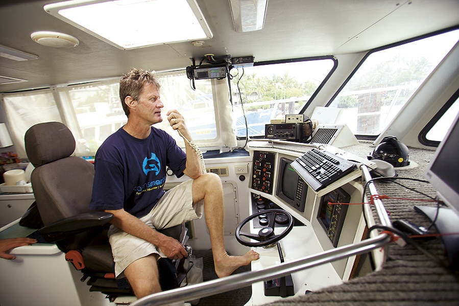 Hombre en la silla del capitán de una lancha escuchando la radio