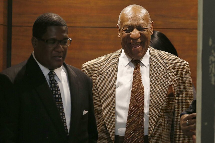 Bill Cosby and an aide exit an elevator.
