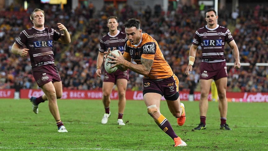An NRL player runs in unimpeded to score a try as his opponents can only watch.