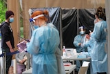 Five health workers in full PPE masks and gowns at a COVID testing centre.