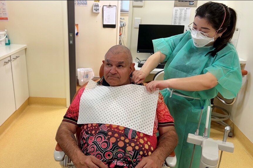 man in red t shirt sits in dentist chair