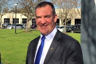 A man in a suit and tie and dark hair looks at the camera