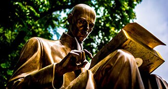 Gold statue of man with book.