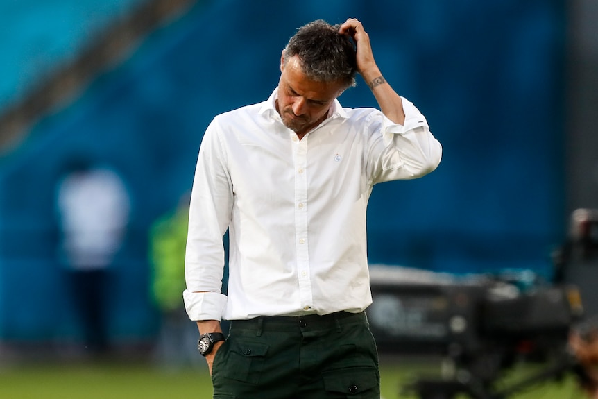 A Spanish team football manager runs his hand through his hair in frustration during a match at Euro 2020