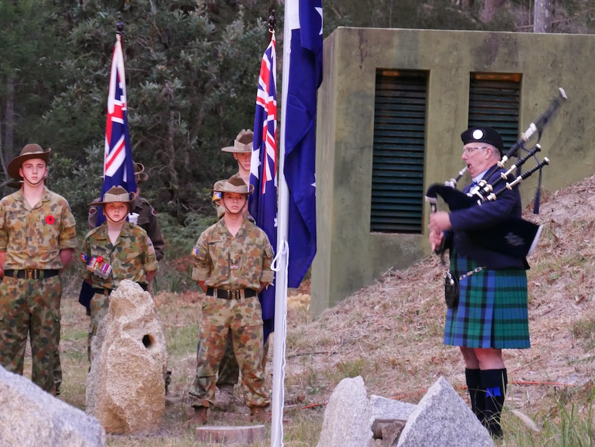 Army cadets and a musician outside of a historic world war two bunker for anzac day.