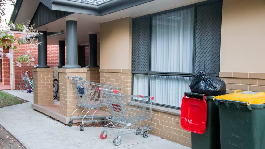 Two shopping trolleys out the front of a house