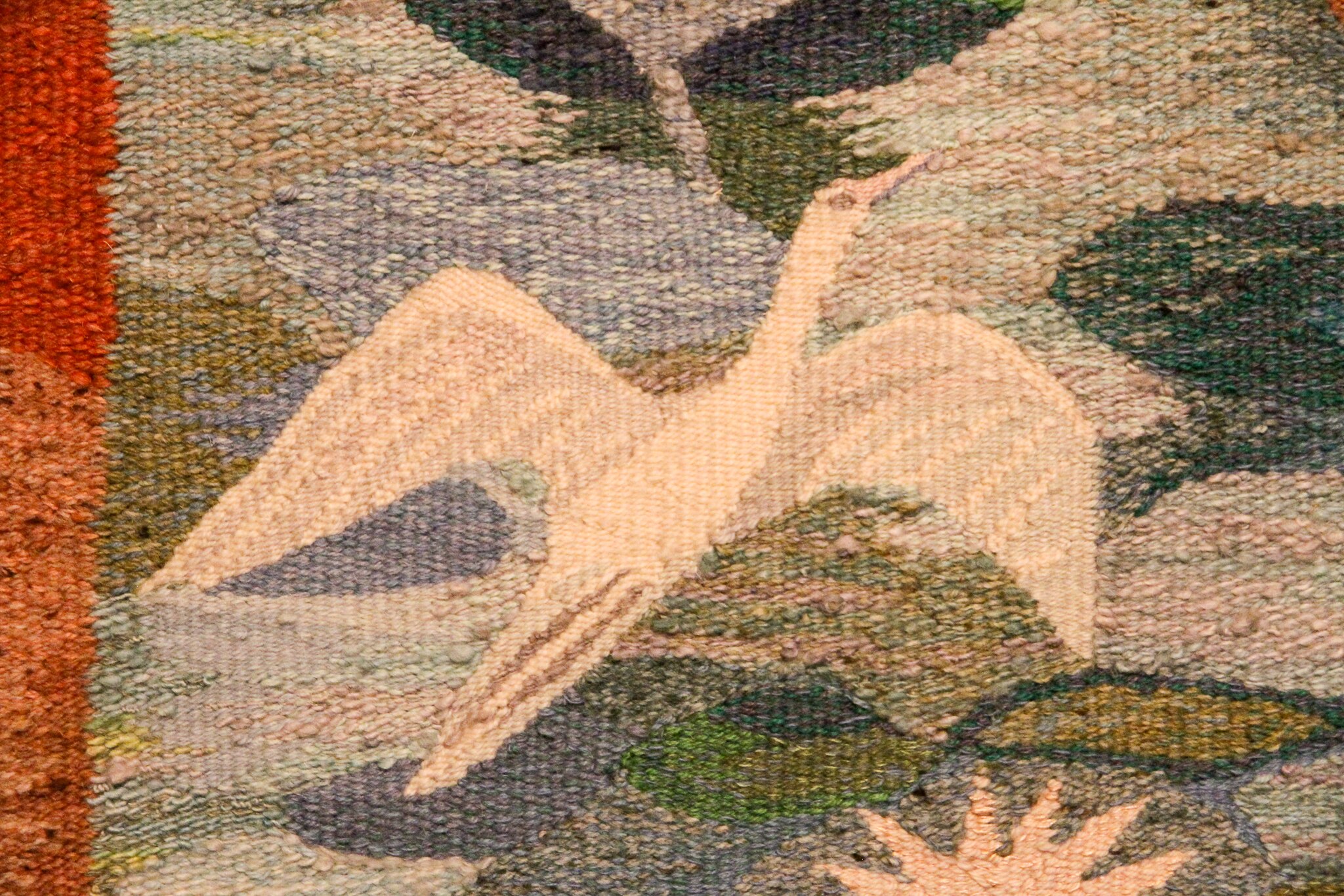 A hand woven egret in a wall tapestry.