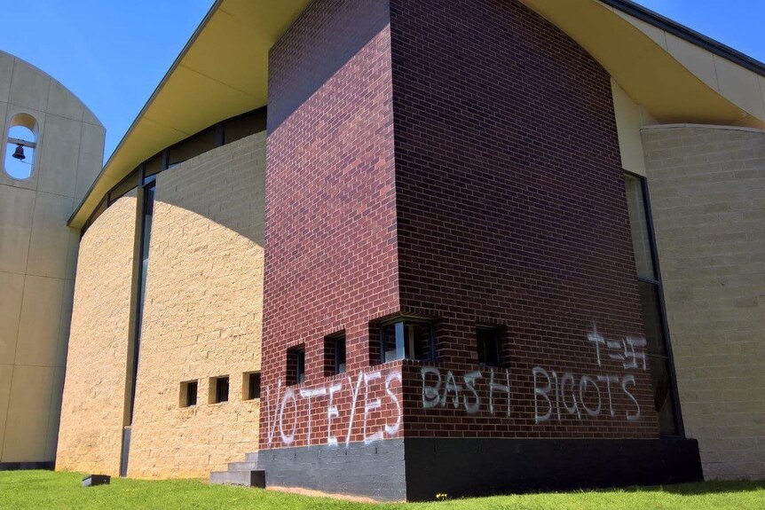 A church wall is defaced with 'Vote Yes' graffiti.