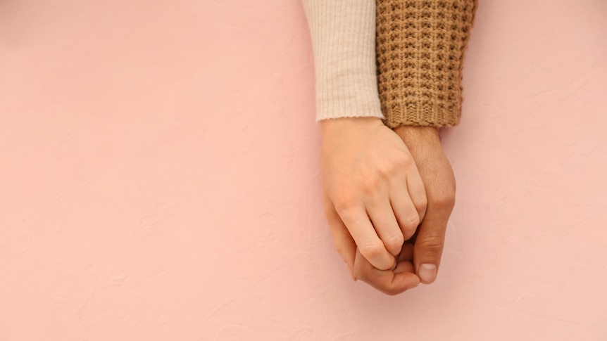 Couple holding hands in a loving way.