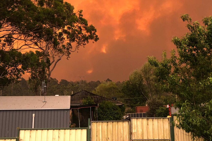 Clouds of red bushfire smoke fill the sky over a residential neighbourhood.