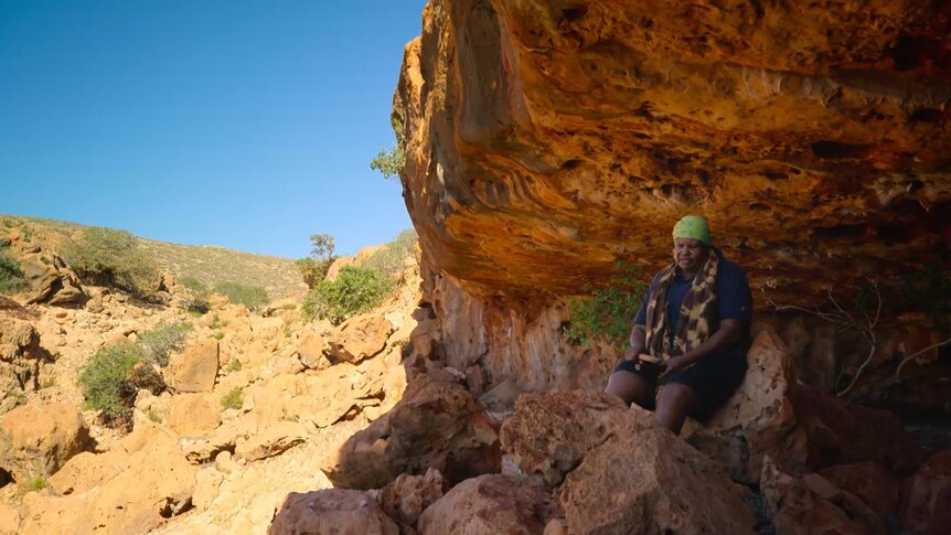 Traditional owner Hazel Walgar sits at the front of a cave at Ningaloo