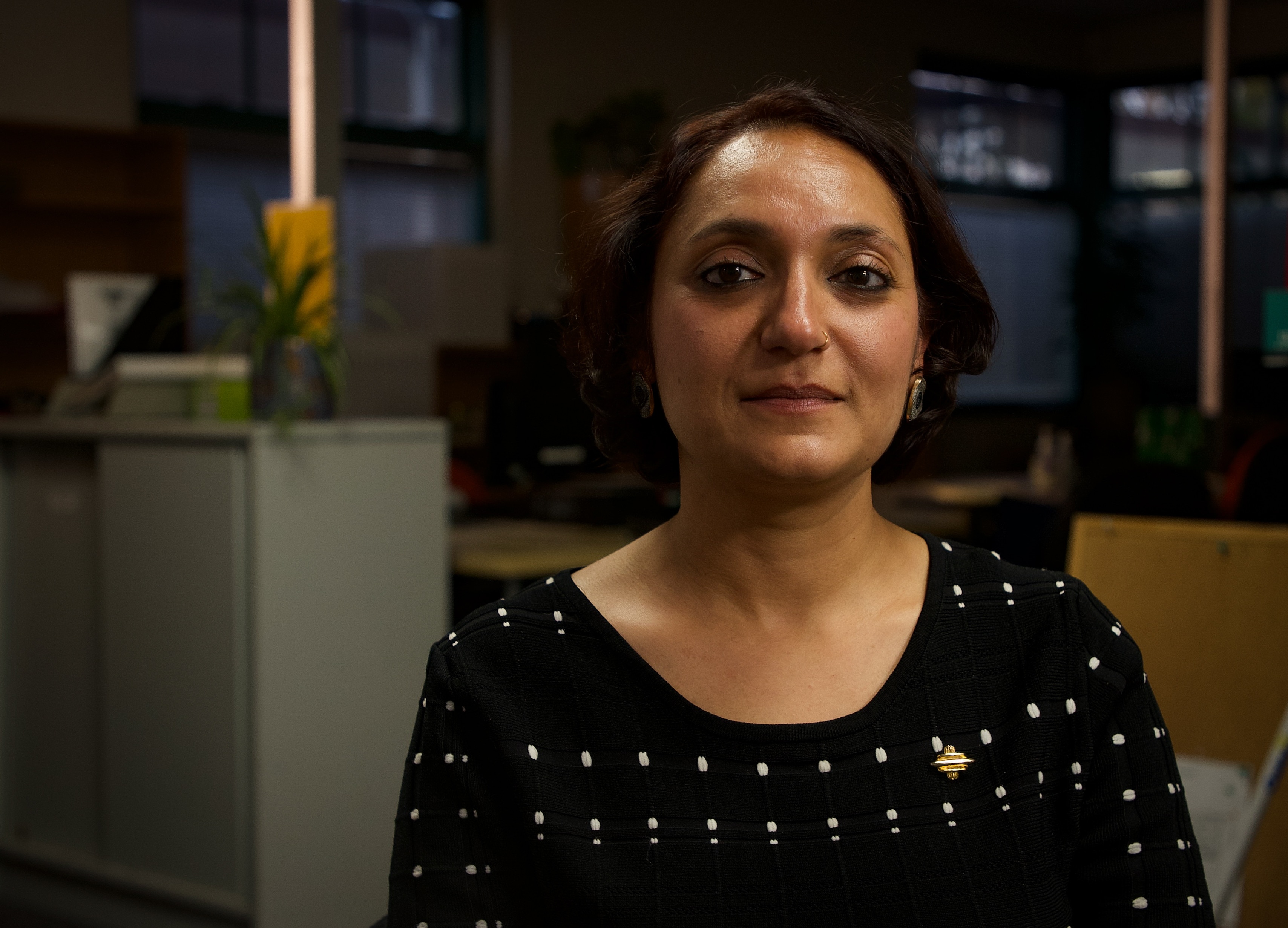 Woman with short brown hair wearing a black top sitting in an office.