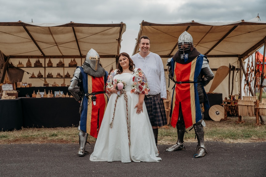 Two knights with dressed in red, yellow and blue, standing with a bride and groom at a medieval-inspired wedding