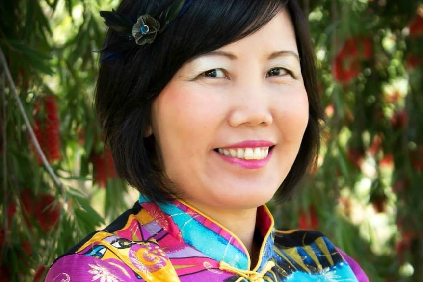 A woman in traditional Asian dress smiles at the camera