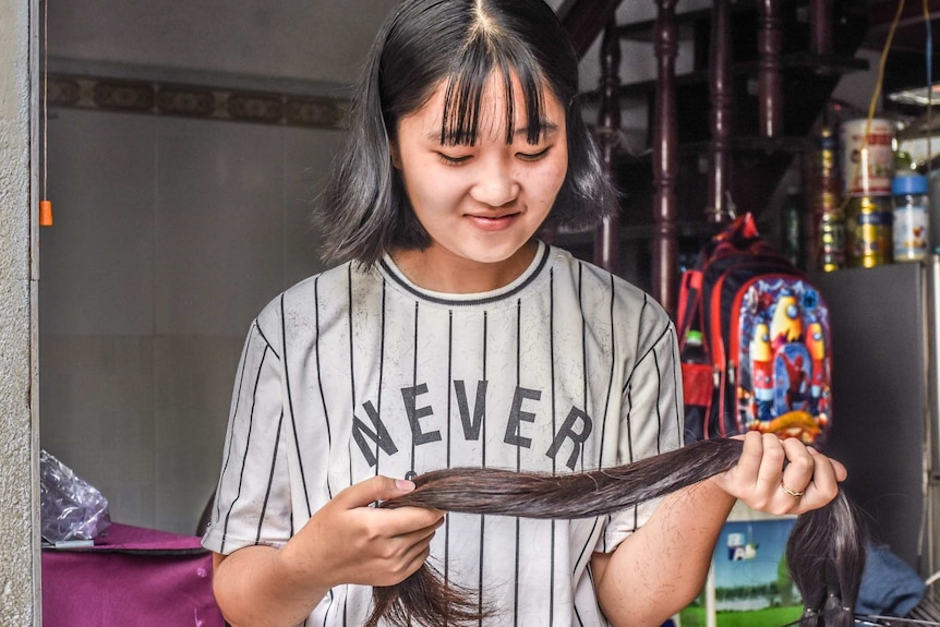 A young woman holds her cut off hair in her hands