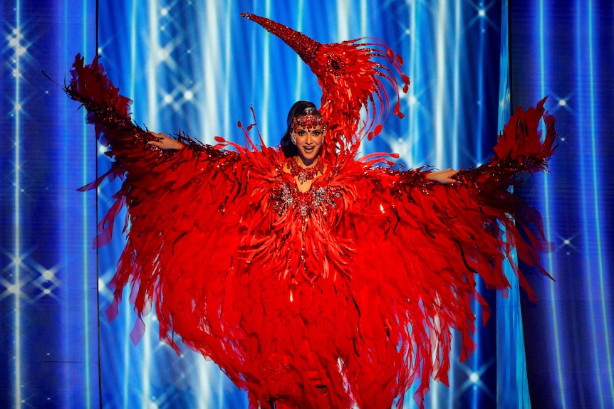 Faith Gillezeau wearing a bright red feathered ibis costume, complete with a glittery beak