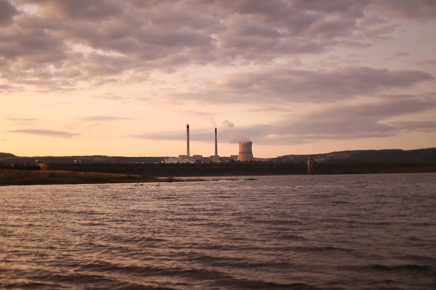 A coal fire power station sitting just behind a large dam.