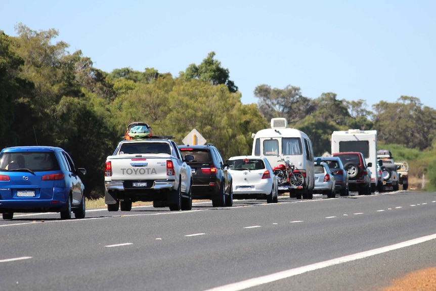 Une gamme de voitures et de caravanes alignées dans la circulation le long d'une autoroute régionale à une voie