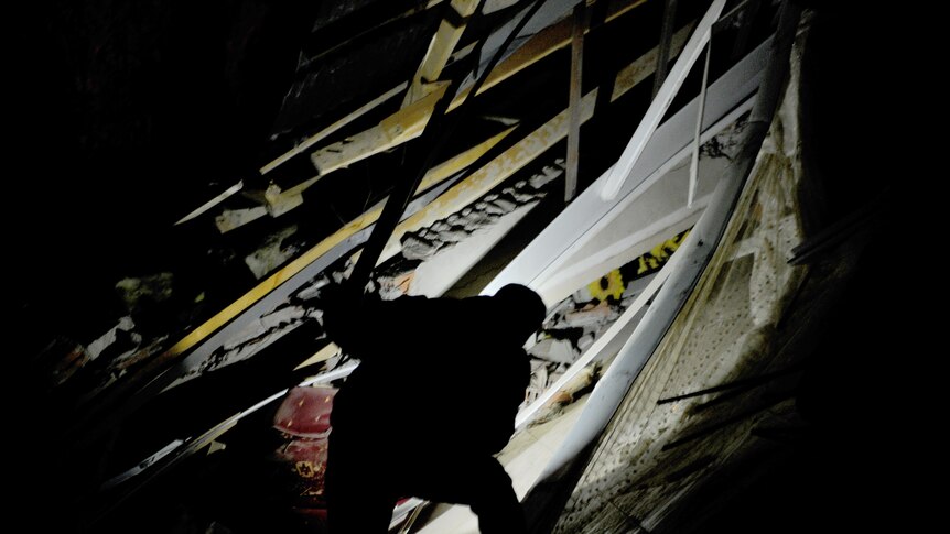 A Turkish man with a torch searches through the rubble of a destroyed building at night in Van on October 23, 2011.