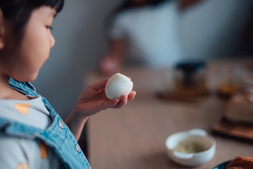 A child looks down at an egg in their hand