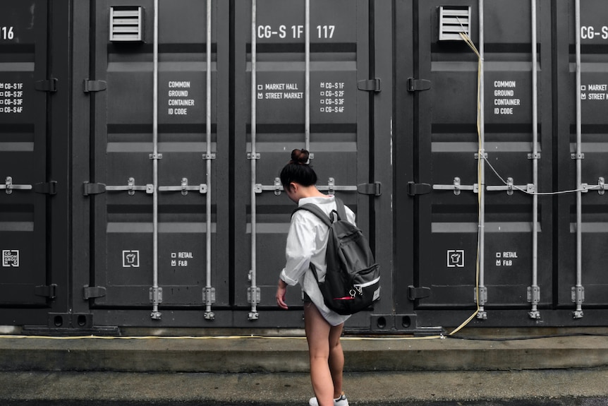 A woman stands in front of a grey door ready to store personal items in a dedicated storage facility