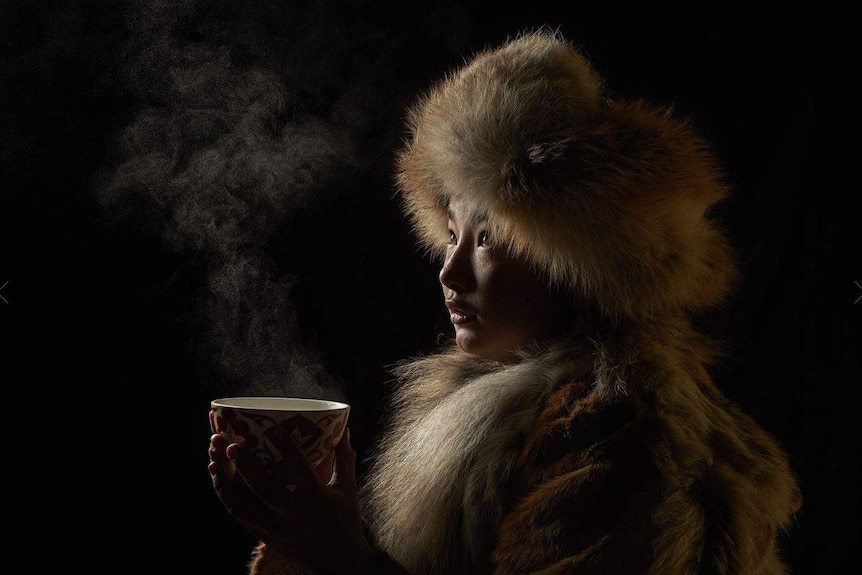 A woman drinks tea in traditional dress