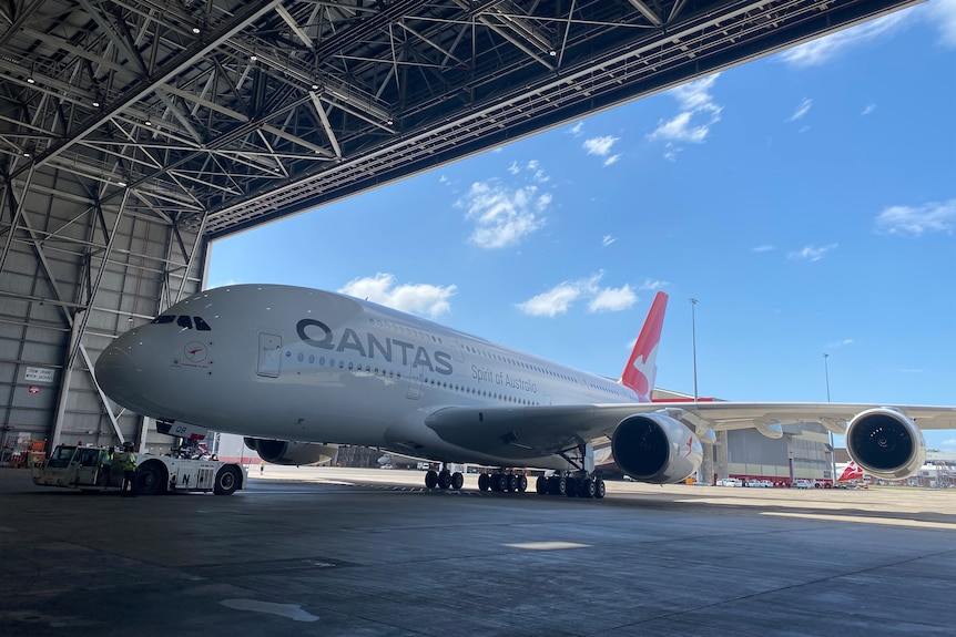 A Qantas plane enters a hanger