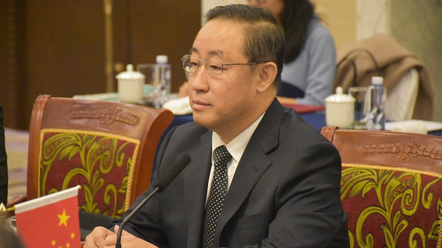 Fu Zhenghua sits at a meeting table.