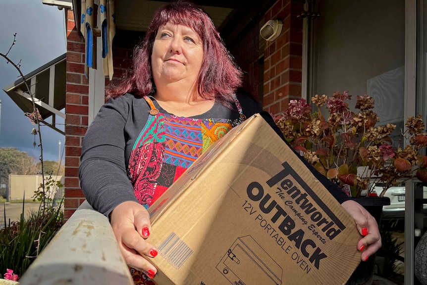 A woman with dark red hair holding a moving box