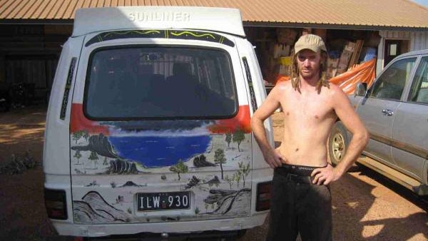 a shirtless young man with dreadlocks stands beside a painted van