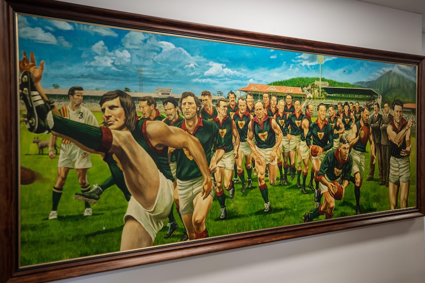 A painting shows a group of AFL players running on to the field.
