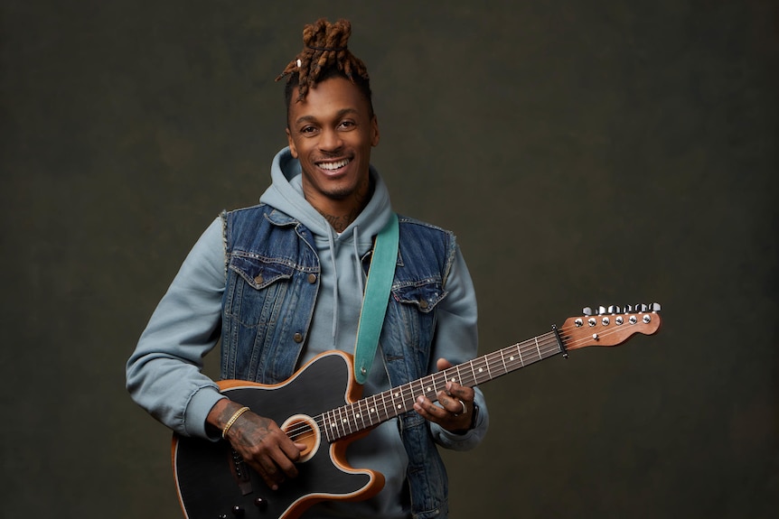 A black man holding a guitar