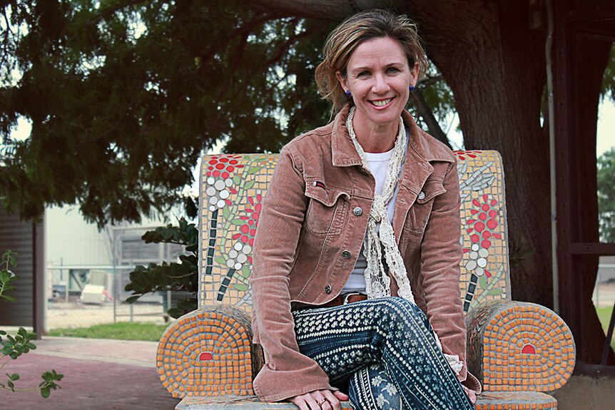 Deborah Keats sits on a mosaic armchair in a small local park.