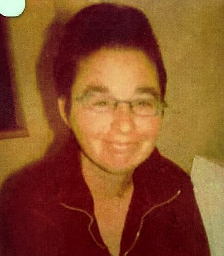 An older photo shows a woman with short brown hair and glasses.