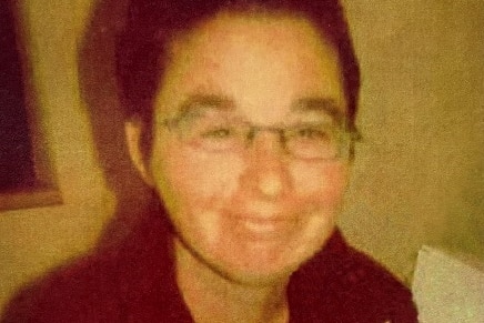 An older photo shows a woman with short brown hair and glasses.