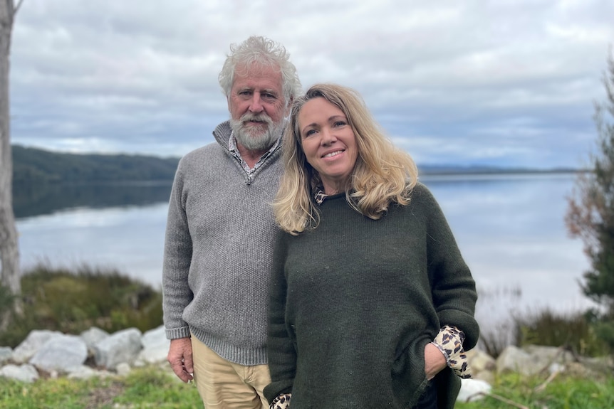 A man and a woman stand next to each other, smiling at the camera.