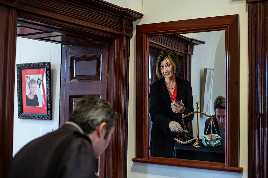 Man looking at detail in portrait of Kate McClymont by artist Peter Smeeth.