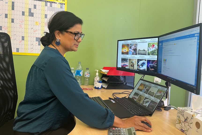 A woman with brown hair using a computer in an office.