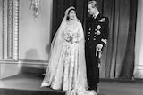 Queen Elizabeth and Prince Philip stand in their wedding outfits.