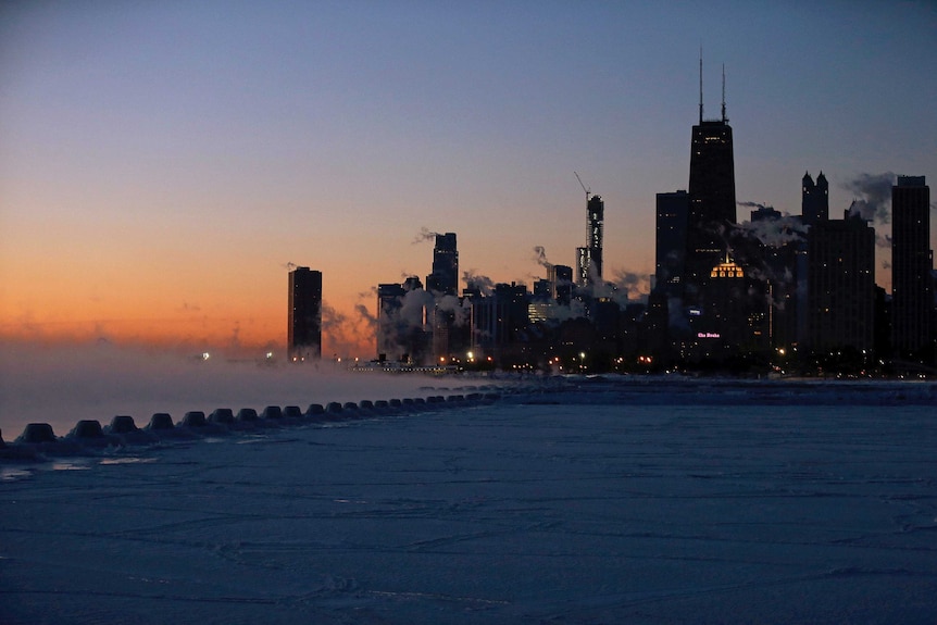 Sun starts to rise over a frozen Lake Michigan and Chicago skyline