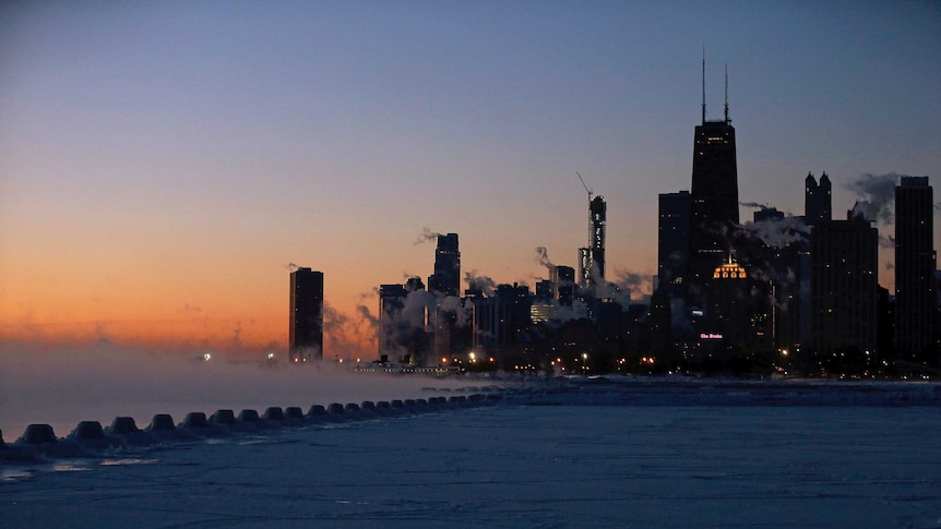 Sun starts to rise over a frozen Lake Michigan and Chicago skyline