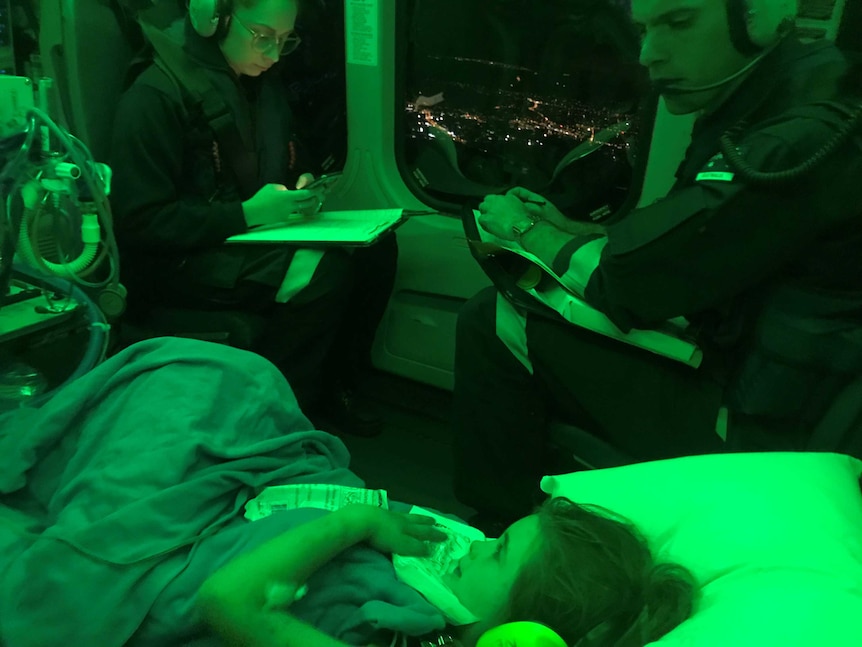 Two paramedics watch over Evie as they fly in a helicopter to hospital.