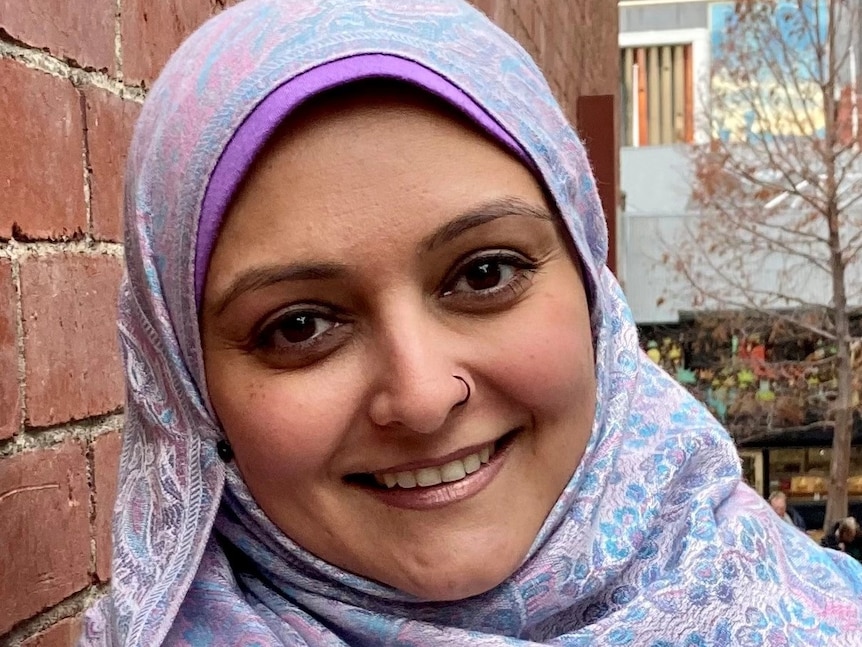 A woman in a pink and blue hajib smiles 