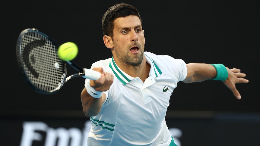 A Serbian male tennis player stretches for a forehand at the 2021 Australian Open.