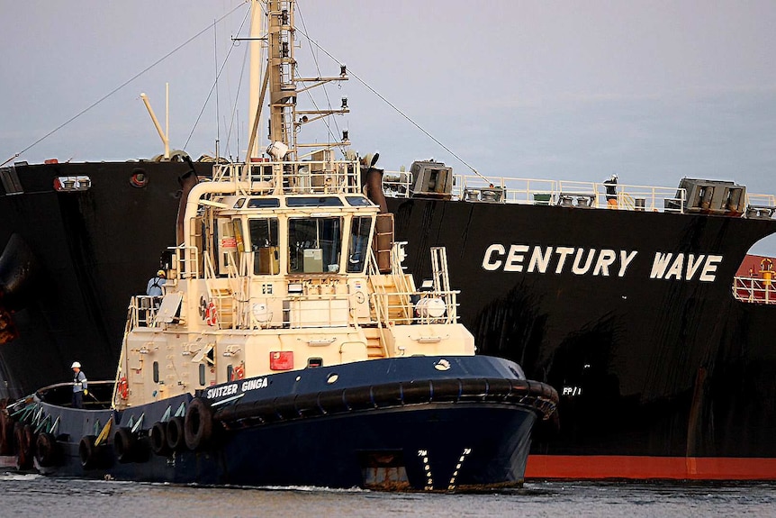 A pilot vessel guides a coal ship towards the harbour entrance at the Port of Newcastle