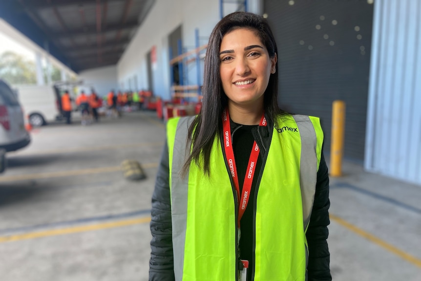 A woman wearing a high-vis vest smiles at camera.