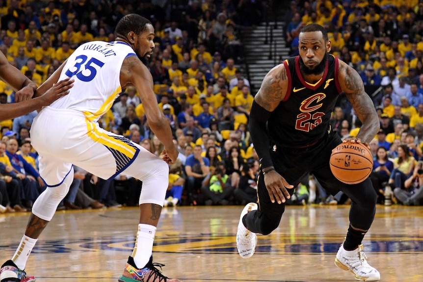 LeBron James of the Cavaliers runs to the outsides of Kevin Durant of the Warriors whilst dribbling the ball in his left hand