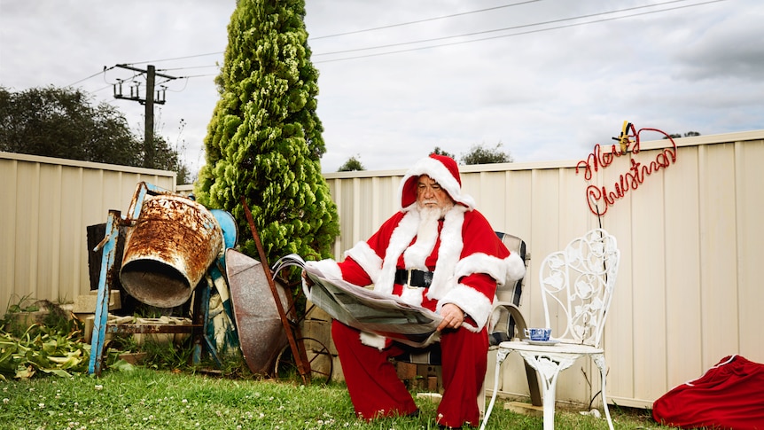 Santa Claus reading the newspaper in a suburban Australian back yard