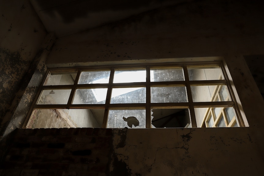 Broken windows inside a dilapidated building with light streaming through from a sunlight